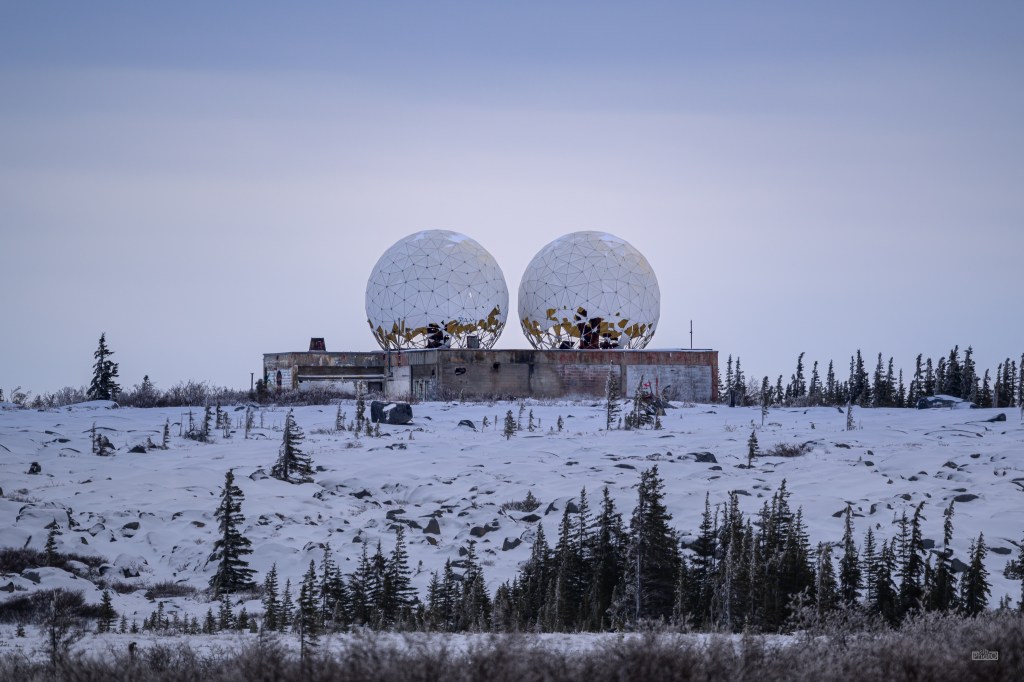 Abandoned radar station at the Churchill Rocket Research Center, surrounded by snow and trees in Manitoba.