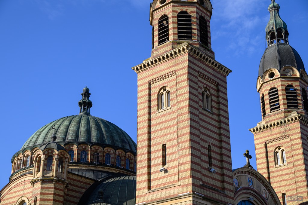 Close-up view of a church with a large dome and two tall towers against a clear blue sky.